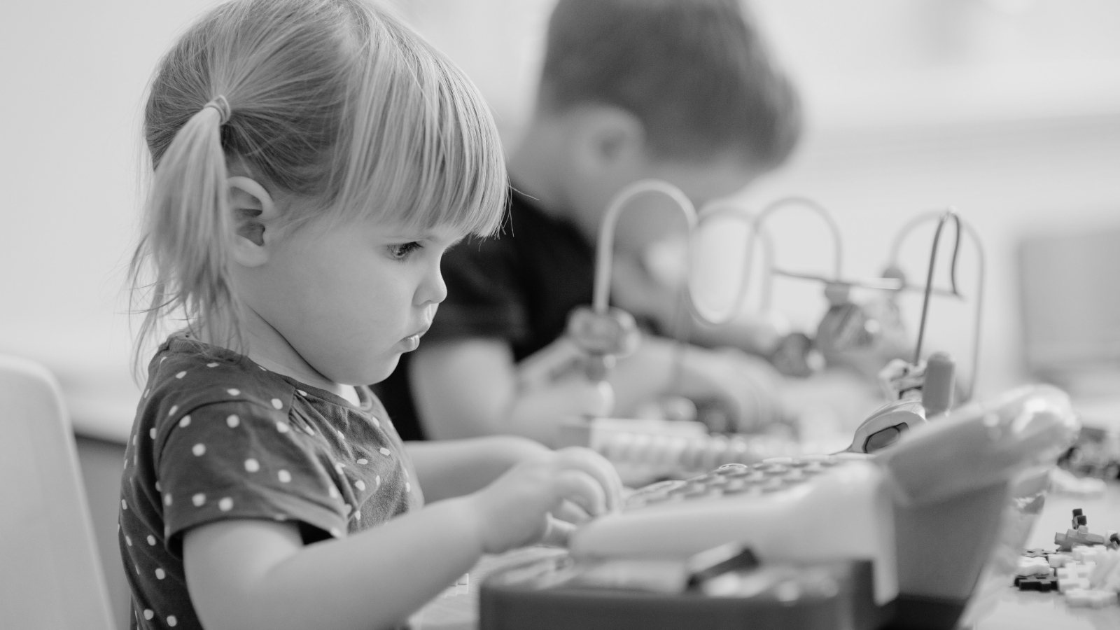 Two young children play in a nursery setting